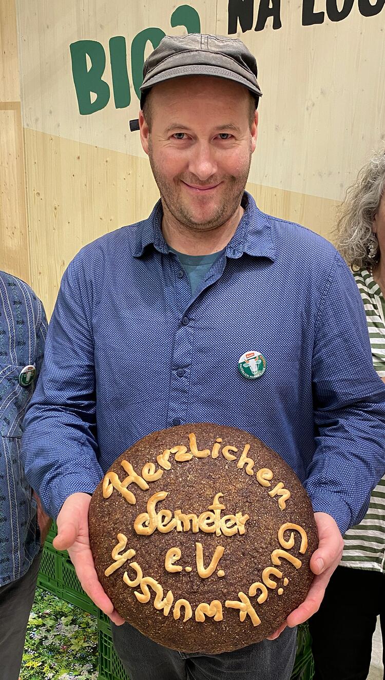 Gewinner mit Brot in der Hand mit der Aufschrift: Herzlichen Glückwunsch Demeter e.V.