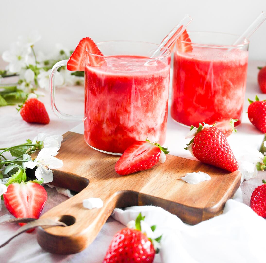Erdbeer-Kefir-Mocktail in Glastassen mit Glasstrohalm angerichtet auf einem Brett mit Erdbeeren