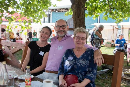 Besucher:innen des Festes sitzen auf einer Bank