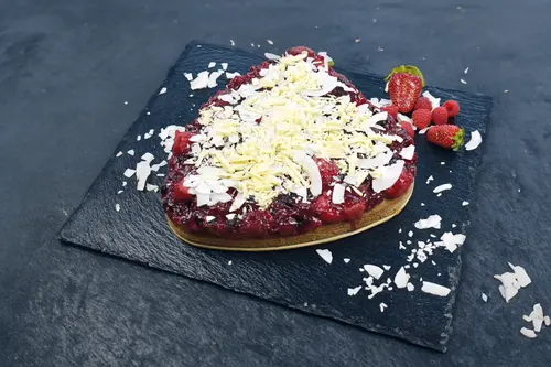 Chia Beeren Kuchen mit Kokoschips auf einer schwarzen Platte garniert mit Erdbeeren